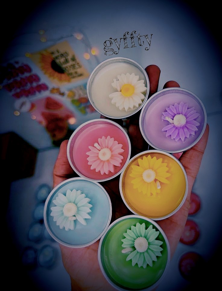 Six daisy tealights in tins, held in one hand