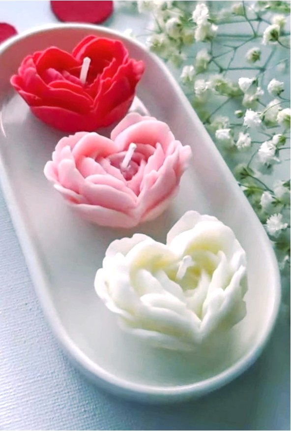 Three rose candles in red, pink and ivory on a ceramic tray